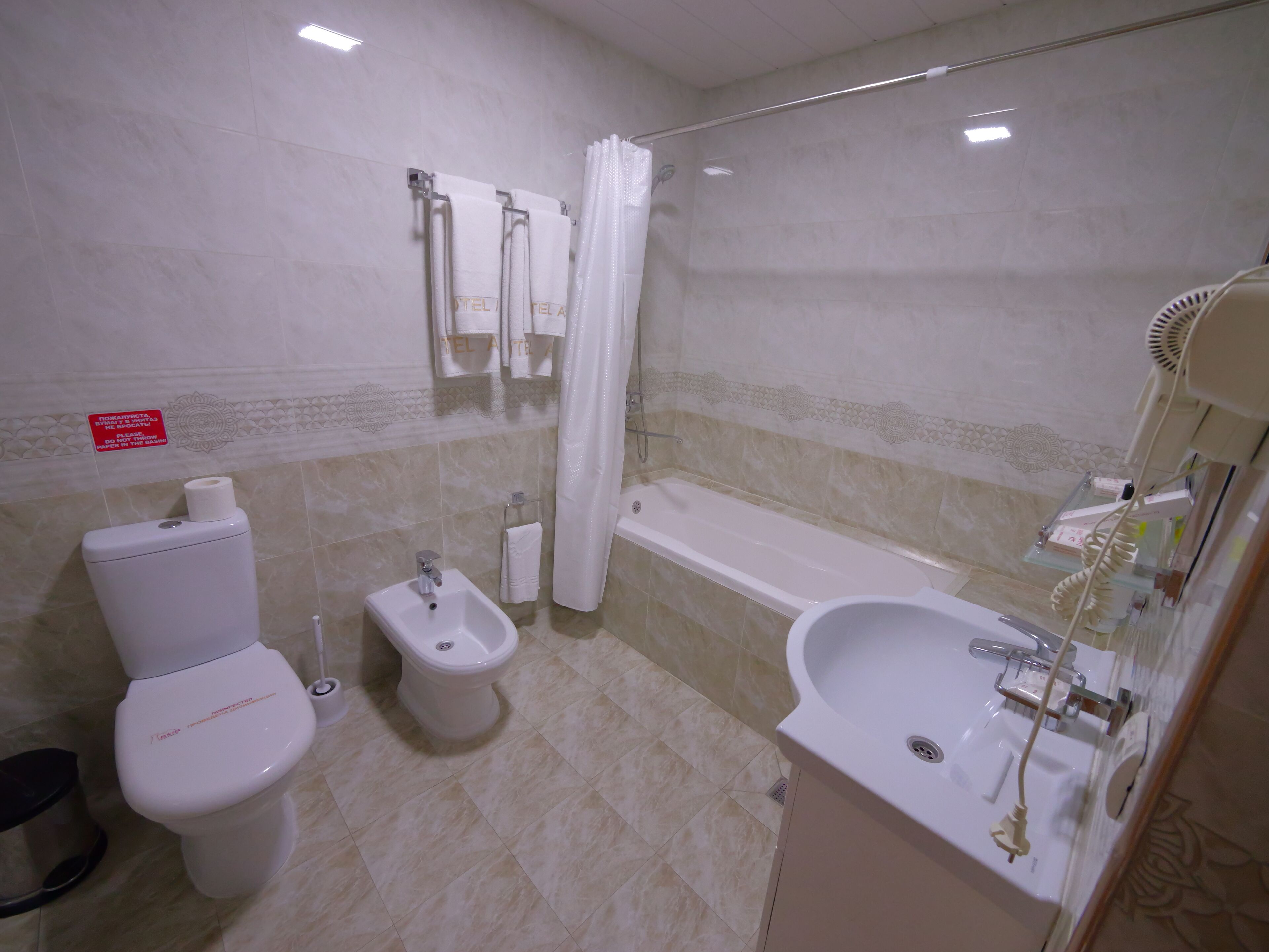 A bathroom with a toilet, bidet, bathtub, and sink.