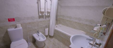 A bathroom with a toilet, bidet, bathtub, and sink.