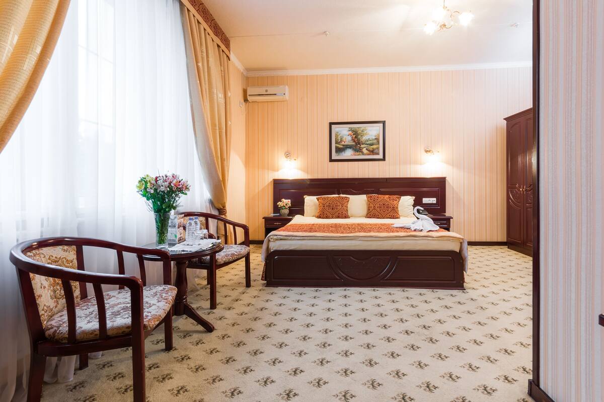 Een hotelkamer met een bed, een stoel, een klein tafeltje en een schilderij aan de muur.