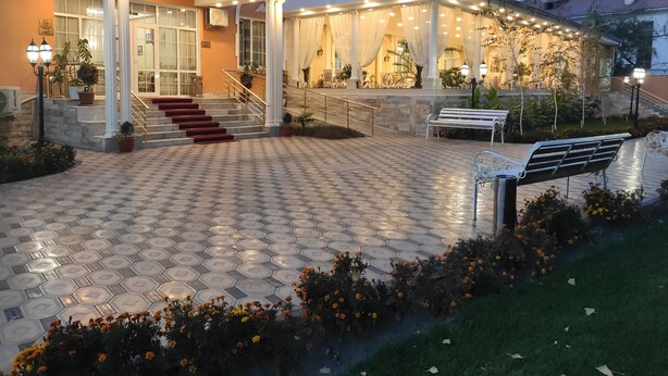 A hotel entrance with a covered walkway, steps, and a bench. - Asia Hotel Fergana (Fergana)