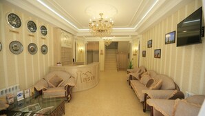 A hotel lobby with a reception desk, seating area, and a chandelier. - Asia Hotel Fergana (Fergana)