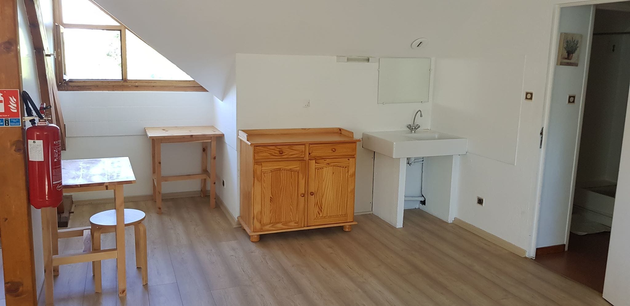 A small, bright kitchen with wooden cabinets, a sink, and a window.