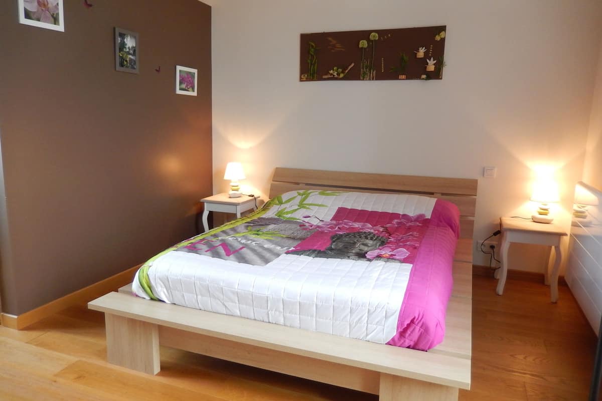 Een slaapkamer met een bed, nachtkastjes en wanddecoratie.
