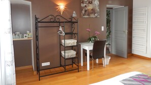 Een slaapkamer met een bed, een bureau, een stoel, een kledingkast en een wandplank met decoratieve objecten.