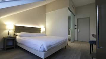 A modern bedroom with a large bed, bedside lamps, a wardrobe, and a door.