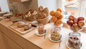 A breakfast buffet with bread, fruits, and jars of spreads. - Hôtel du Théâtre (Yverdon-les-Bains)