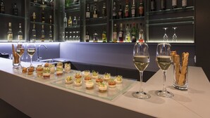 A bar area with neatly arranged bottles and glasses, and a display of appetizers on a glass tray. - Hôtel du Théâtre (Yverdon-les-Bains)