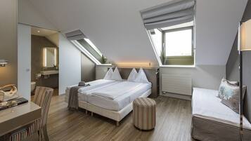 A modern bedroom with a large bed, a desk, and a small seating area.