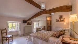 Ein Schlafzimmer mit einem großen Bett, Holzbalken, einem Kronleuchter und einem Fenster mit Blick.