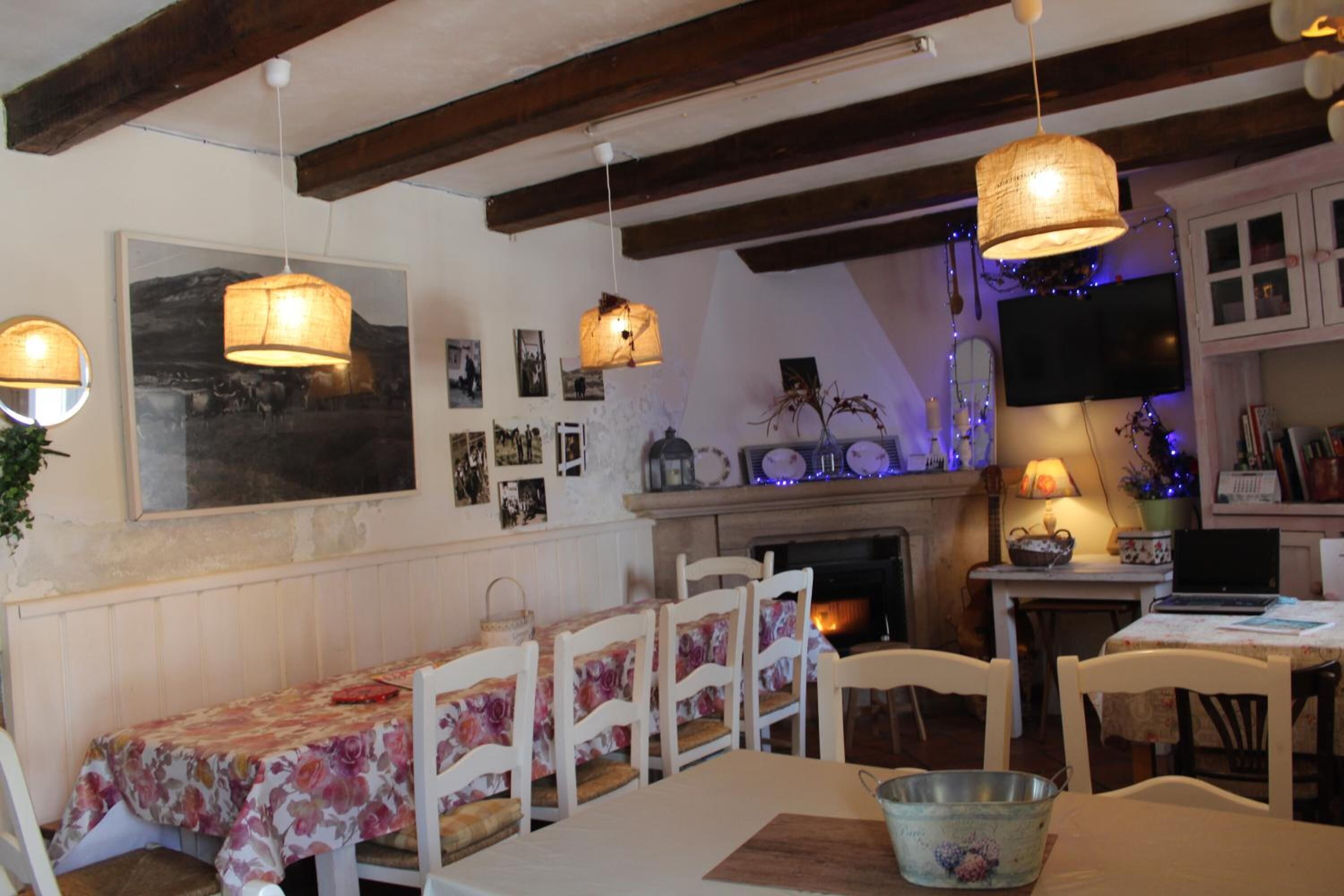 Un comedor con una mesa dispuesta para cuatro, sillas de madera, una chimenea y lámparas colgantes.