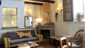 Ein gemütliches Wohnzimmer mit einer Couch, Sesseln, einem Kamin und Wandleuchten.