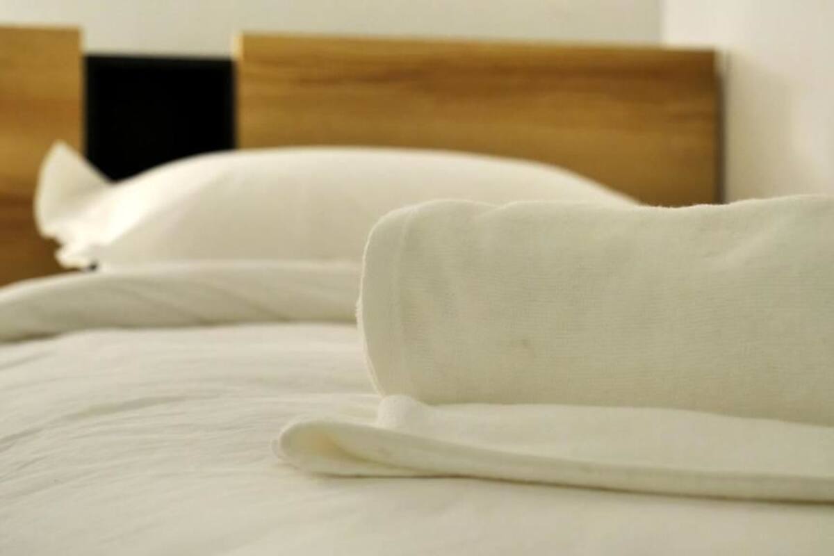 A neatly made bed with white linens and a wooden headboard.