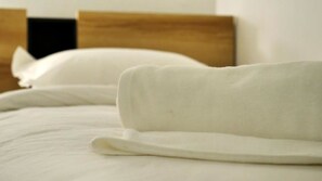 A neatly made bed with white linens and a wooden headboard.
