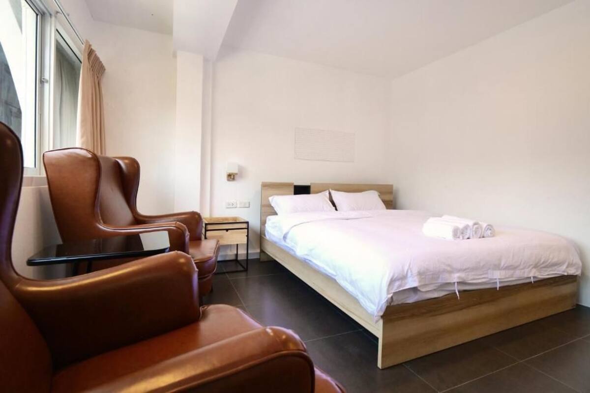 A hotel room with a bed, a seating area with chairs, a small table, and a nightstand.