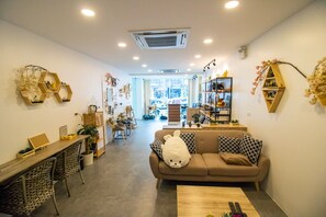 A cozy living room with a sofa, chairs, a coffee table, and a bookshelf. - Breeze Hostel Pattaya (Pattaya)