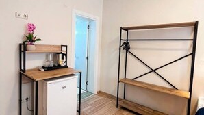 A compact kitchenette with a refrigerator, a coffee maker, and a shelf with a flower. - Blue Sea Hotel (Tuzla)