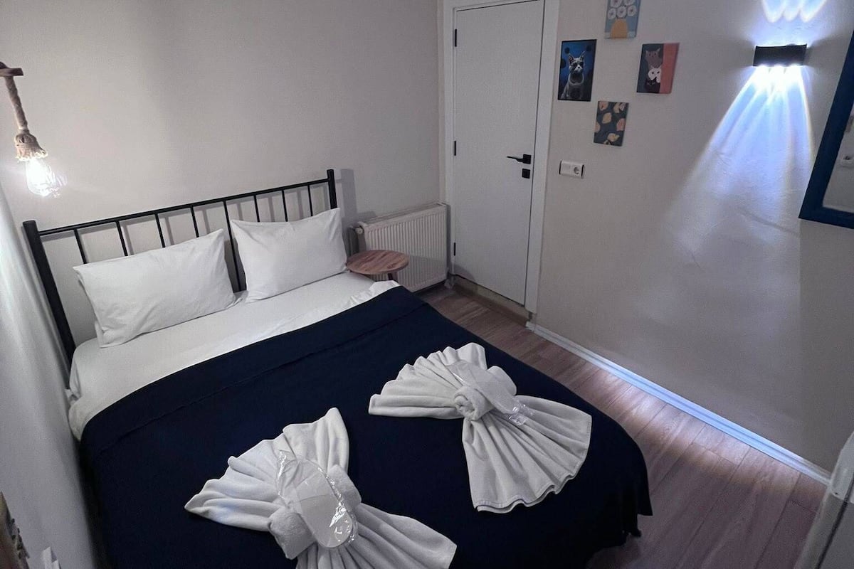 A hotel room with a bed, a door, and wall-mounted artwork.