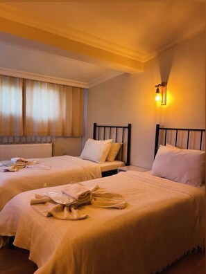 A hotel room with two beds, a window with curtains, a wall-mounted light, and a radiator. - Blue Sea Hotel (Tuzla)