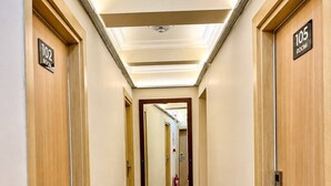 A hotel hallway with wooden doors, numbered room signs, and a reflective floor. - Blue Sea Hotel (Tuzla)