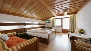 Ein Zimmer mit Holzwänden, einem Bett, einem Schlafsofa, einem kleinen Tisch und einem Fernseher.