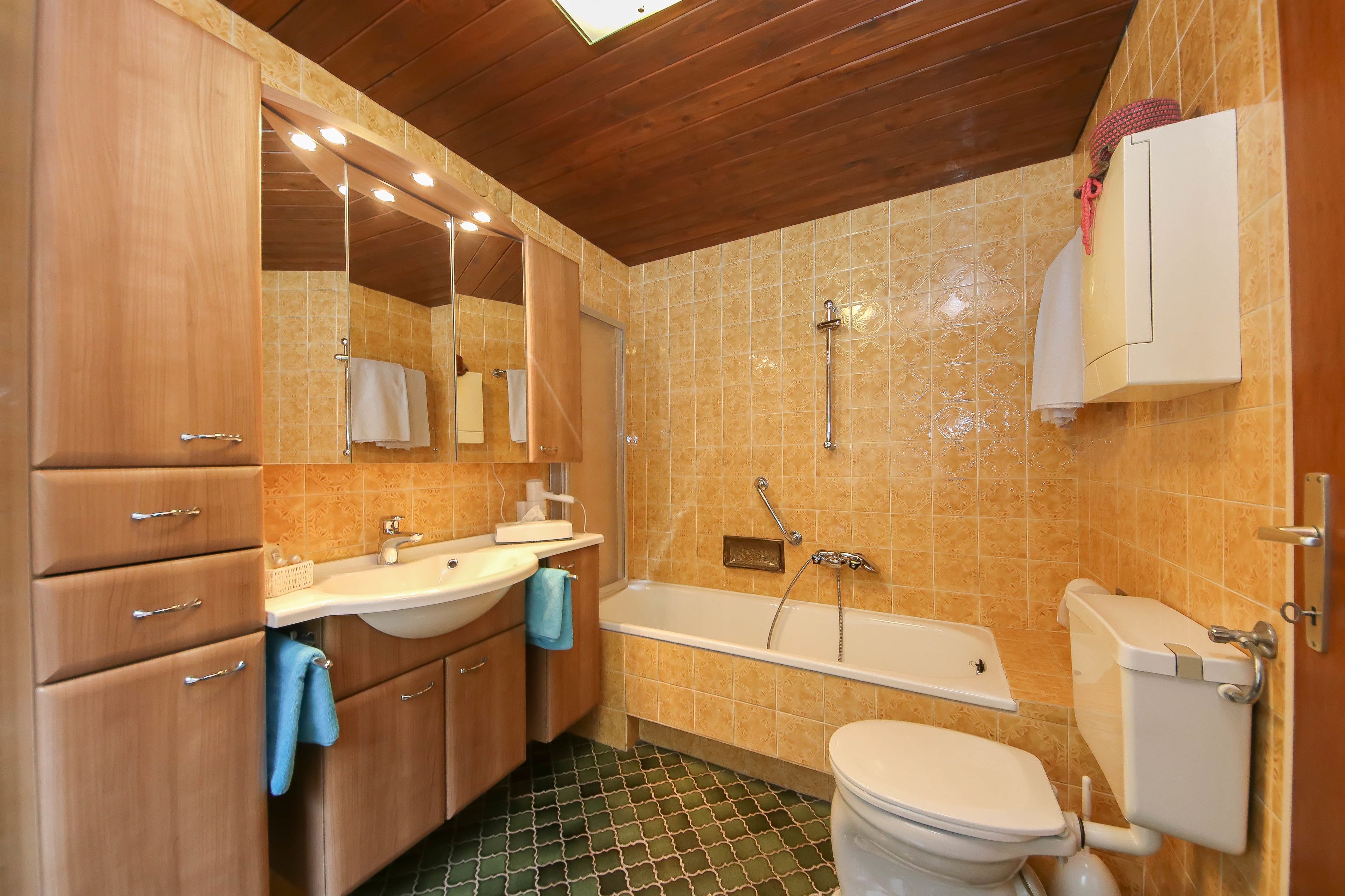 A bathroom with a wooden vanity, a sink, a bathtub, and a toilet.