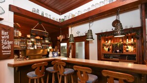 Eine Barbereitschaft mit Holzhockern, Regalen voller Flaschen und hängenden Lampen.