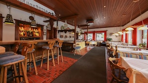 Ein Restaurantinneres mit Holzhocker, Tischen und hängenden Pendelleuchten.