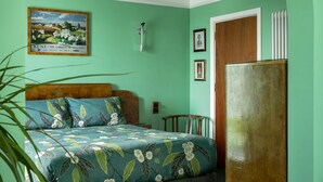 A bedroom with a bed, a wooden wardrobe, a hanging light fixture, and a framed picture on the wall. - Twentieth Century B&B (Birchington)