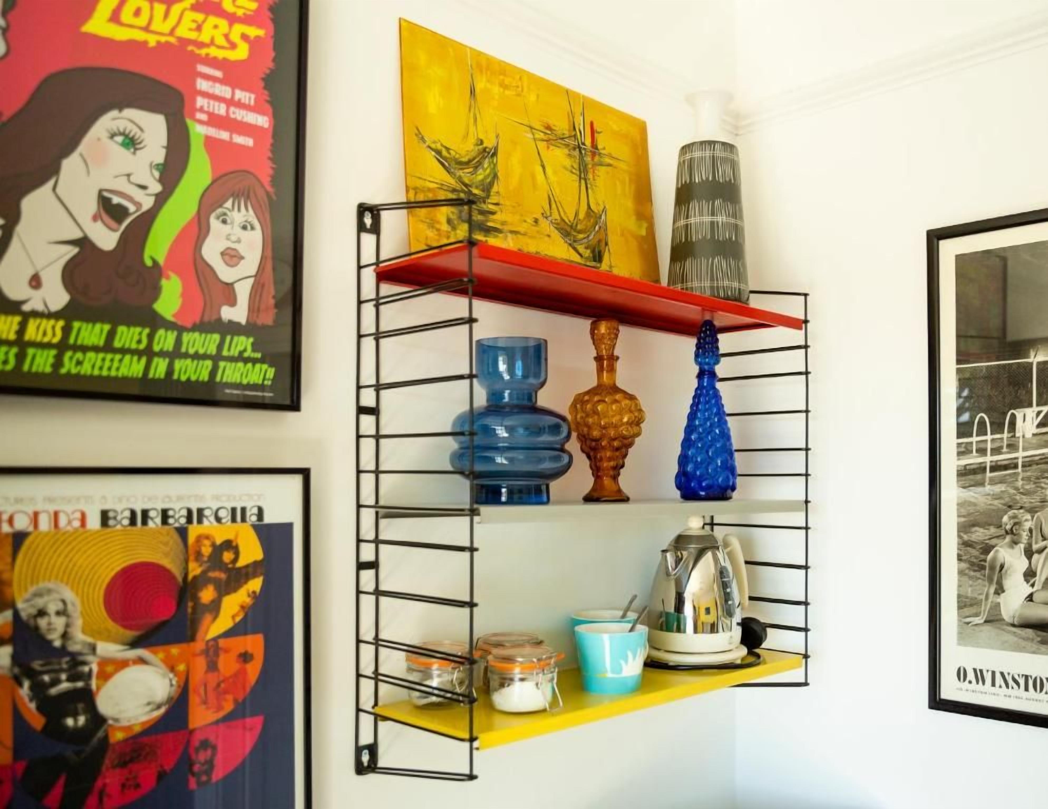 A shelf with various decorative items and two framed posters.