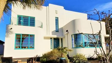 A modern two-story building with a white facade and green accents, including windows and doors.