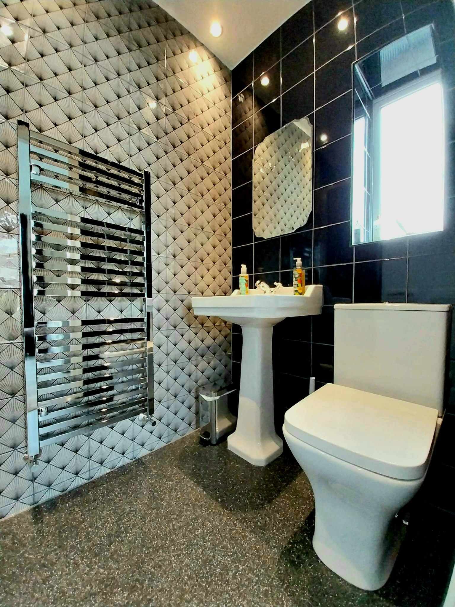 Un baño moderno con pared acolchada, un lavabo y un inodoro.