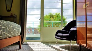 A bedroom with a bed, a chair, a wardrobe, and a view through a window. - Twentieth Century B&B (Birchington)