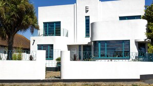 A modern building with a white facade, blue window frames, and a balcony with a railing. - Twentieth Century B&B (Birchington)