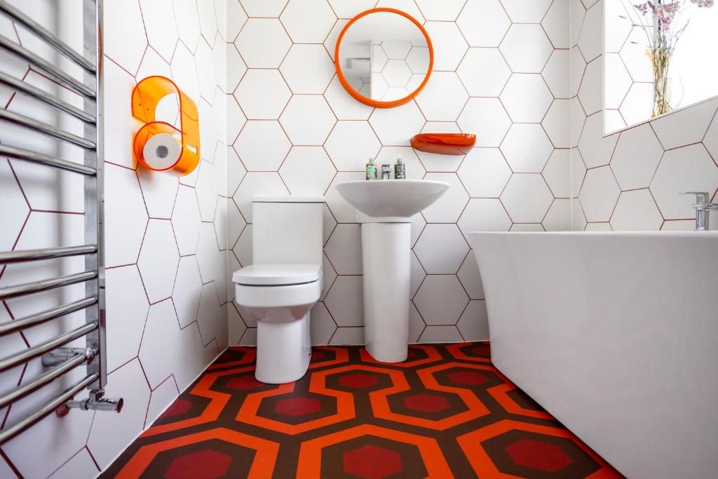 A bathroom with a white toilet, a white sink, and a white bathtub. There is a towel rack on the left and a mirror above the sink.