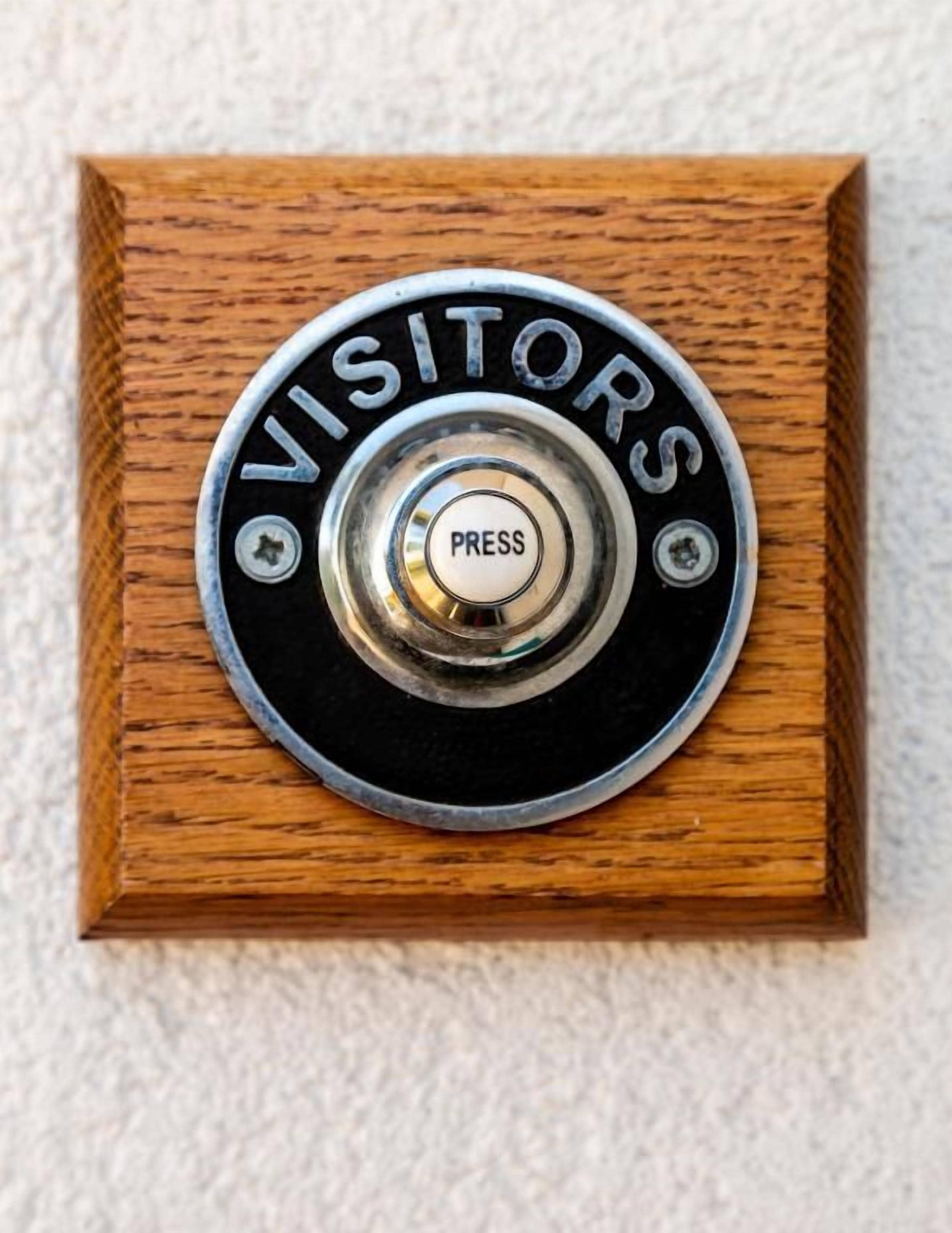 A wooden doorbell with 'VISITORS' and a 'PRESS' button.