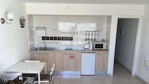 A compact kitchen with a dishwasher, microwave, and a small dining area with a table and chairs. - Holiday Apartment, Beautiful one bedroom apartment, near to all amenities (Puerto del Carmen)
