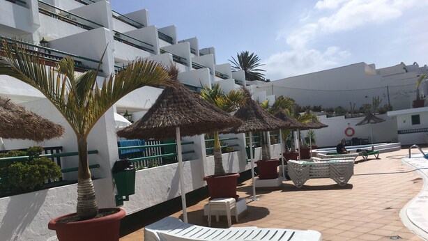 A rooftop pool area with lounge chairs, potted plants, and umbrellas. - Holiday Apartment, Beautiful one bedroom apartment, near to all amenities (Puerto del Carmen)