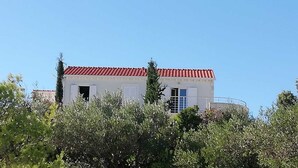 Um edifício branco com telhado vermelho, rodeado por vegetação.