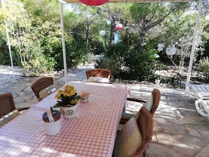 An outdoor patio with a checkered tablecloth, wicker chairs, and a potted plant. - Apartments Grbin - Adults Only (Lumbarda)
