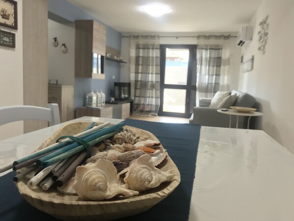 A dining table with a wooden bowl containing seashells and chopsticks.