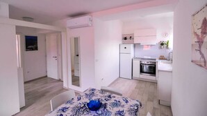 A compact kitchen with a refrigerator, oven, and sink. There is a dining area with a table and chairs. - Apartments An Ni - Adults Only (Korcula)
