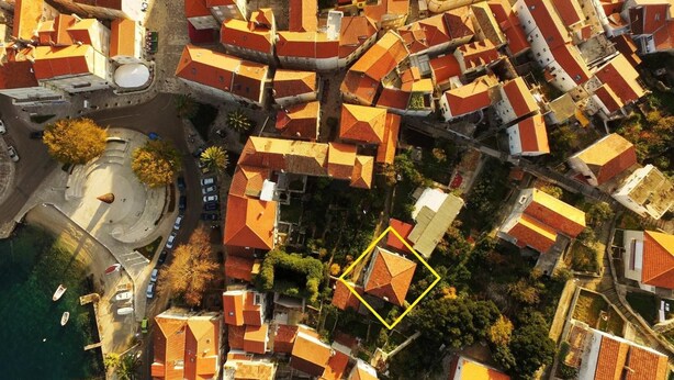 An aerial view of a densely packed urban area with closely built red-roofed buildings, a circular plaza, and a body of water. - Apartments An Ni - Adults Only (Korcula)