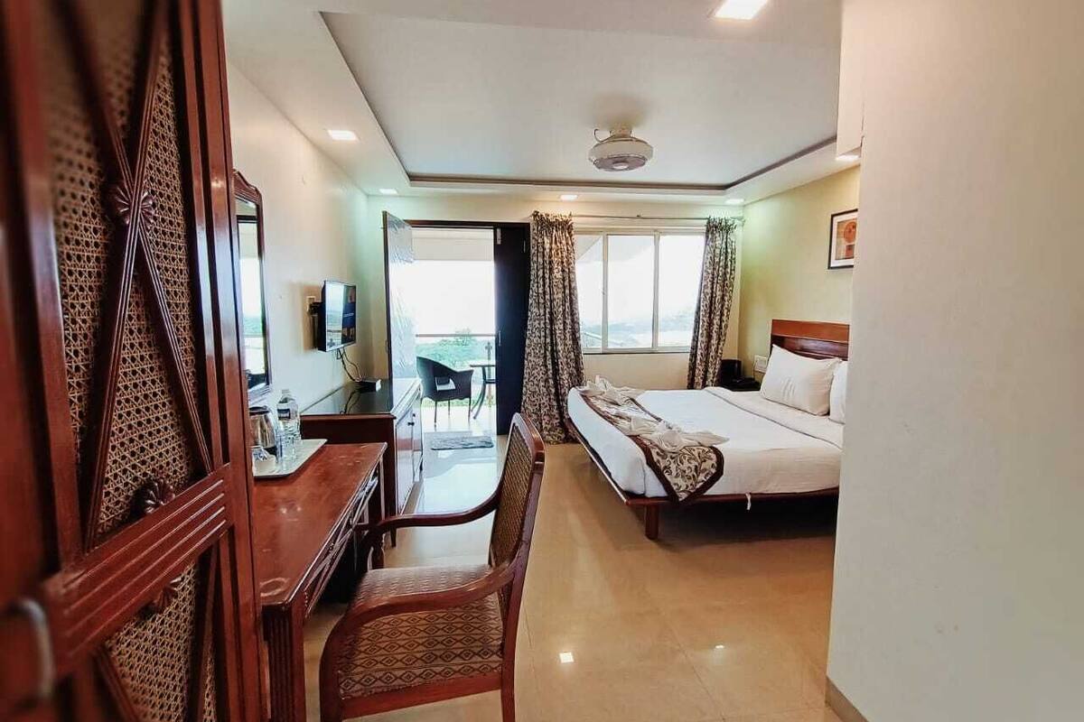 A hotel room with a bed, a desk, a chair, and a TV.