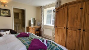 A bedroom with a bed, a wooden wardrobe, a desk with a mirror, and a window with curtains. - Plas Penaeldroch Manor (Dolwyddelan)