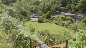 A lush garden with a wooden staircase leading up to a viewing platform. - Plas Penaeldroch Manor (Dolwyddelan)