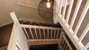 A spiral staircase with white railings and a hanging light fixture. - Plas Penaeldroch Manor (Dolwyddelan)