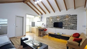 A modern living room with a sofa, coffee table, and a TV mounted on a brick wall.