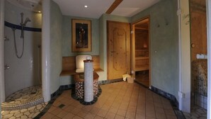 Une salle de bain équipée d’une douche, de toilettes, d’un lavabo et d’une porte en bois.