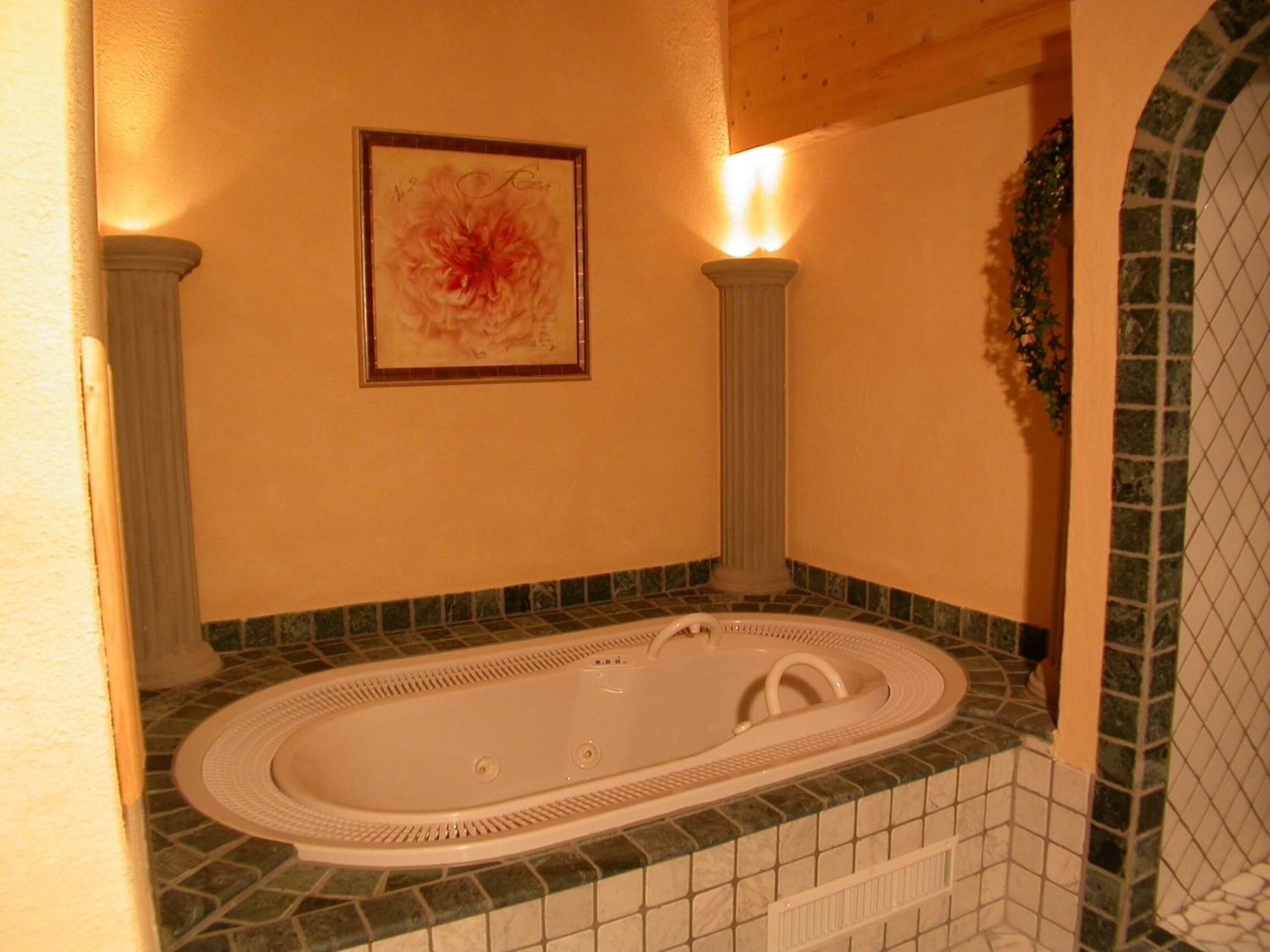 A bathroom with a freestanding bathtub, a framed floral artwork on the wall, and a mosaic tile backsplash.