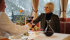 Une table à manger ornée d’un vase de fleurs, d’une bougie et d’un verre à vin.